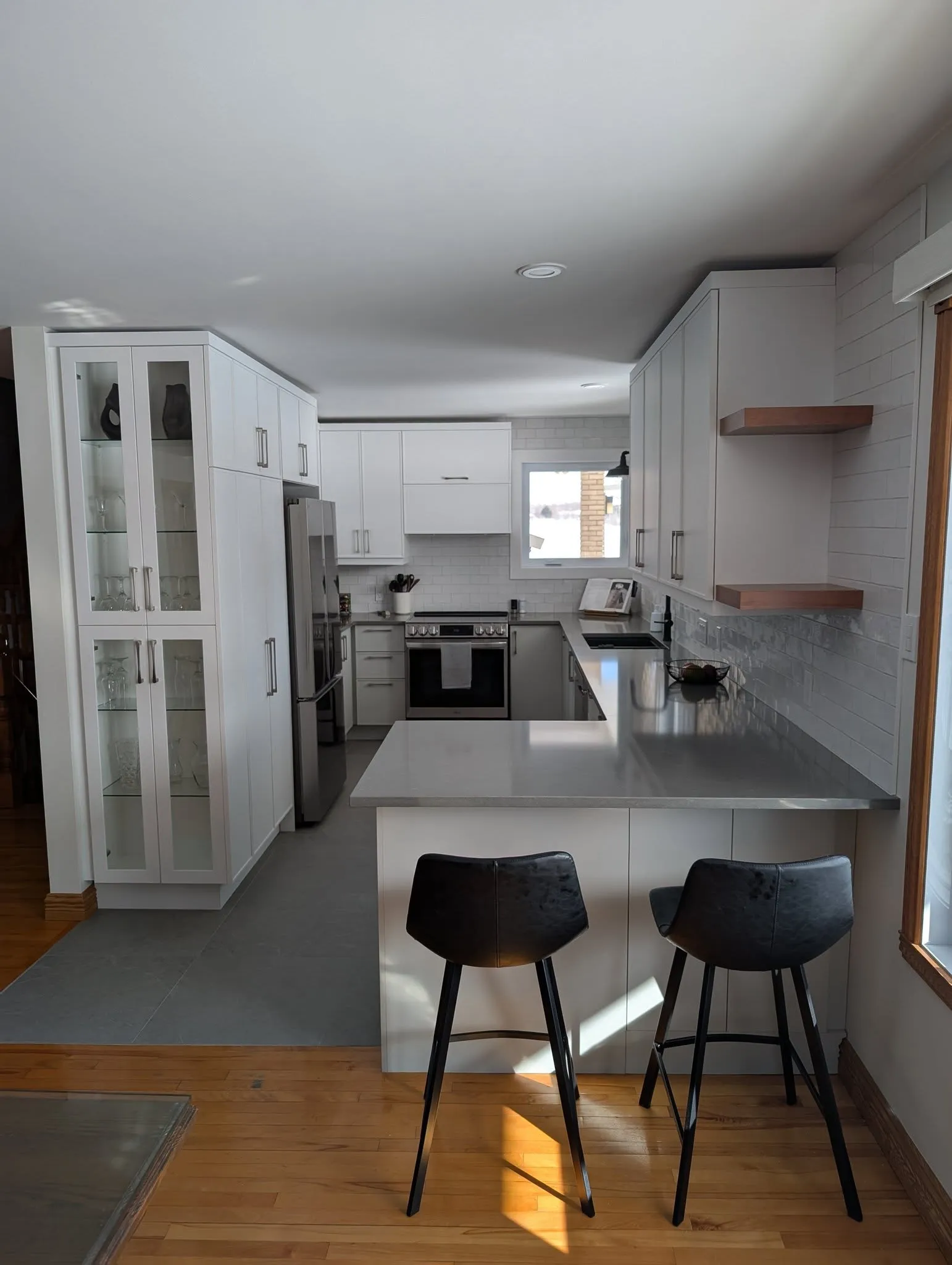 Cuisine blanche rénovée avec armoires pleine hauteur, portes vitrées et comptoir gris